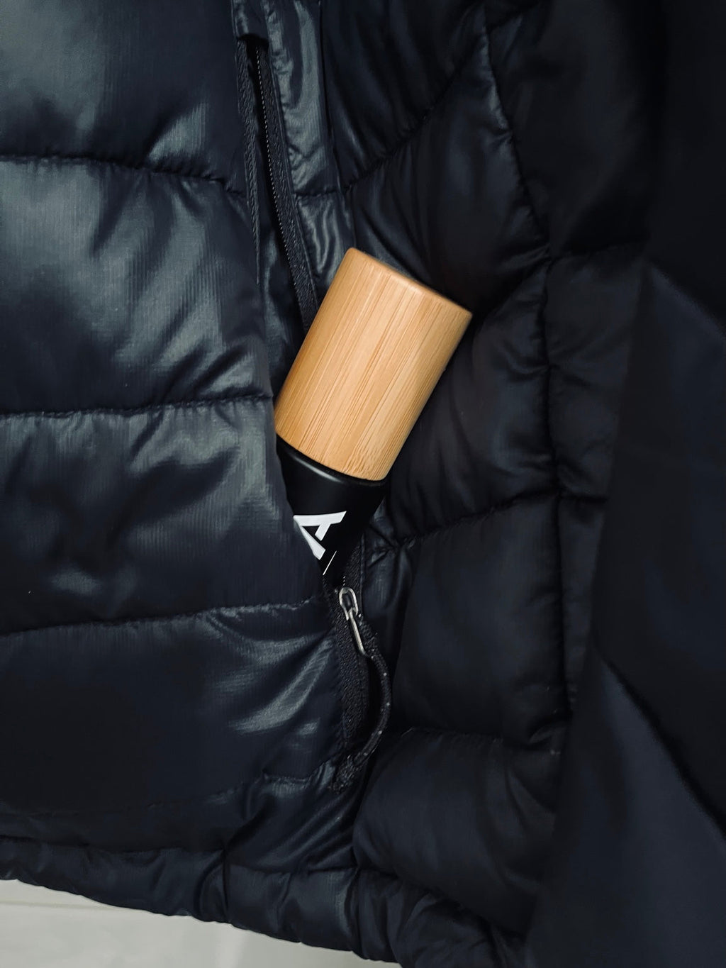 Panda Zero black bottle with bamboo cap tucked into black jacket pocket