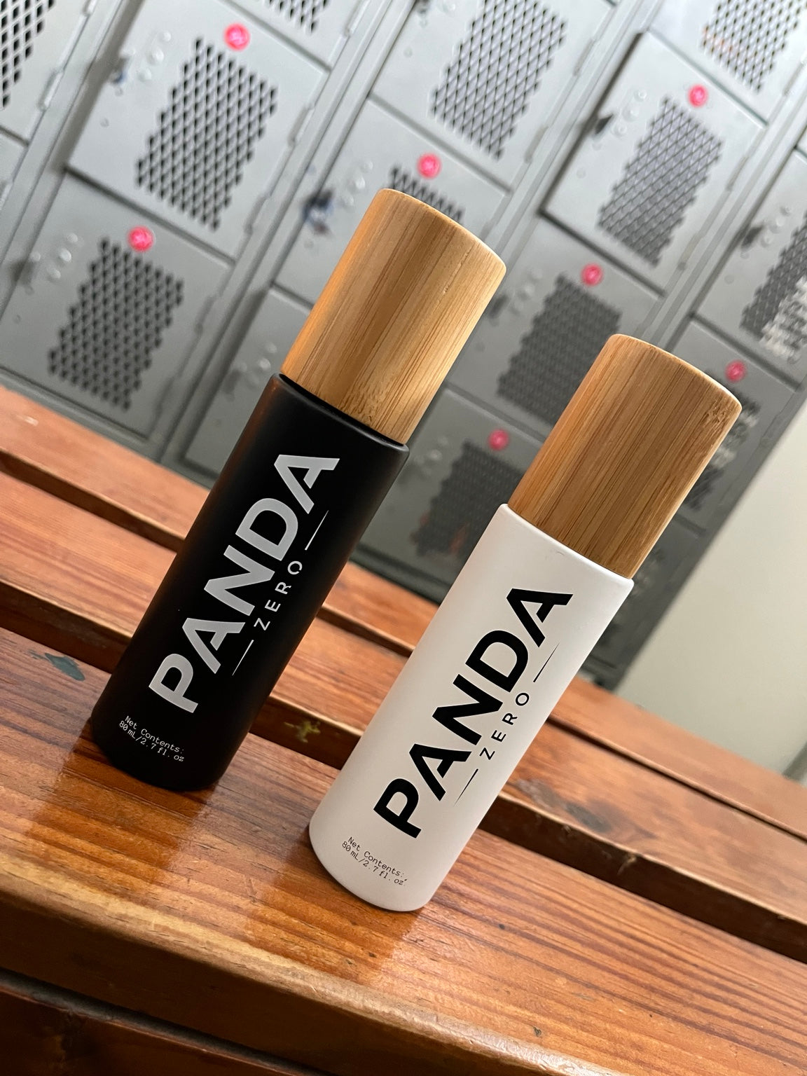 Panda Zero black and white bamboo cap body spray bottles on wooden bench in gym locker room